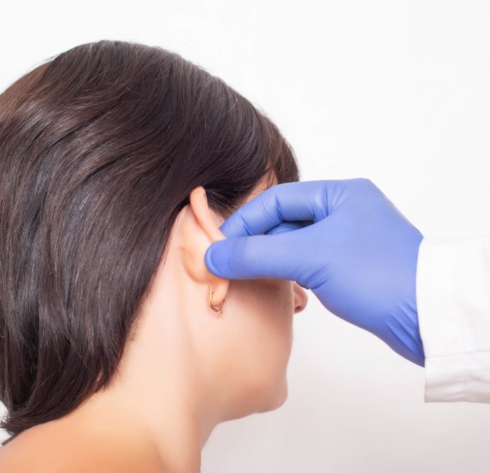 A plastic surgeon doctor examines a patient s girl s ears before performing an otoplasty surgery